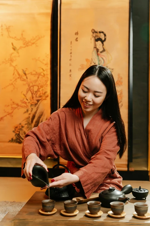 a woman kneeling down near a pile of chinese tea pots