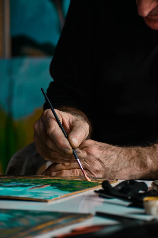 a man is holding a pencil while painting in the dark