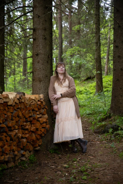 a woman in white dress leaning on a tree