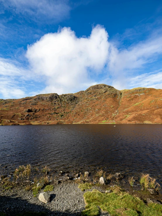 a mountain range with water on one side and grass on the other