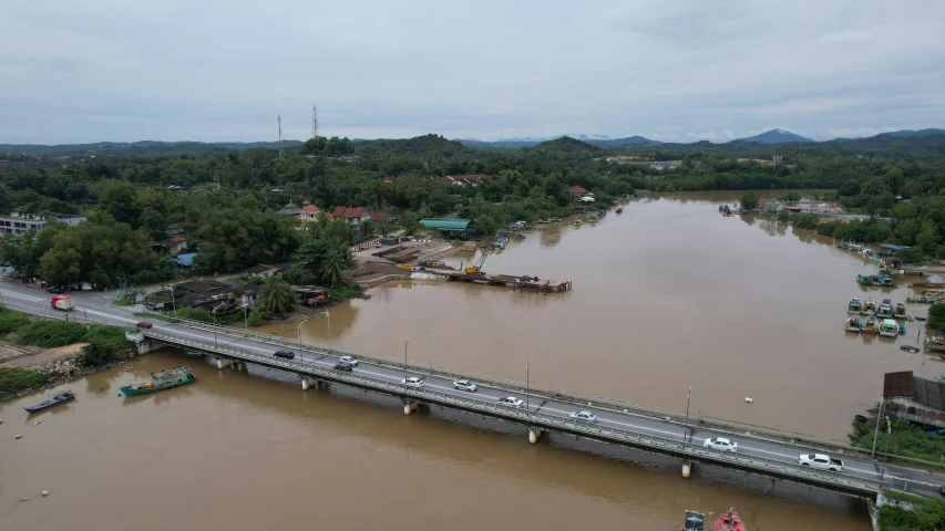 flooded waterway with a bridge and some vehicles crossing it