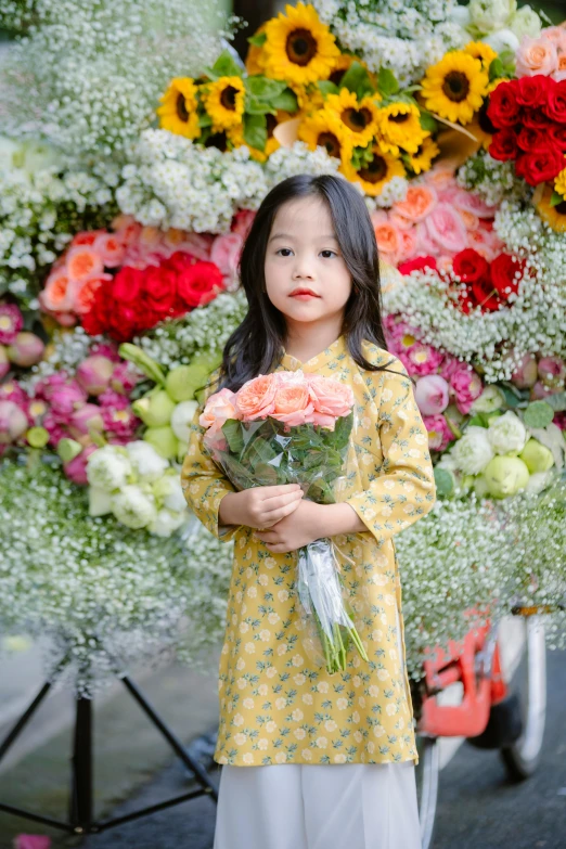 a  in yellow dress holding pink and red flowers