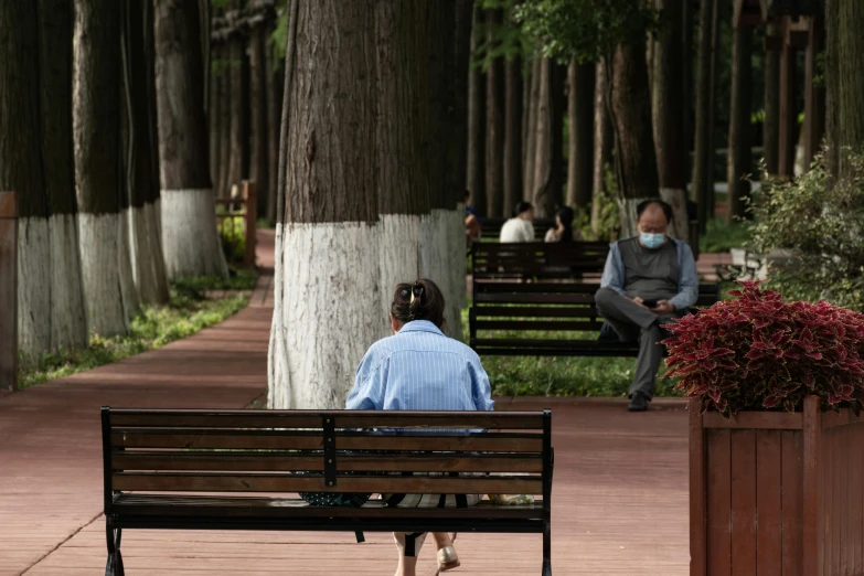 two women sit on park benches as one of them looks away