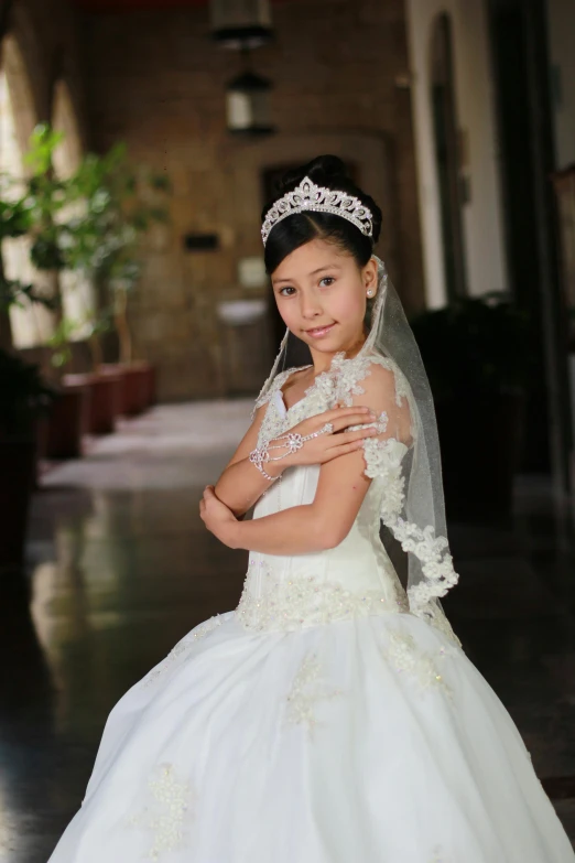 a little girl wearing a white dress and veil