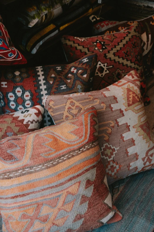 a number of different patterned pillows on a bed