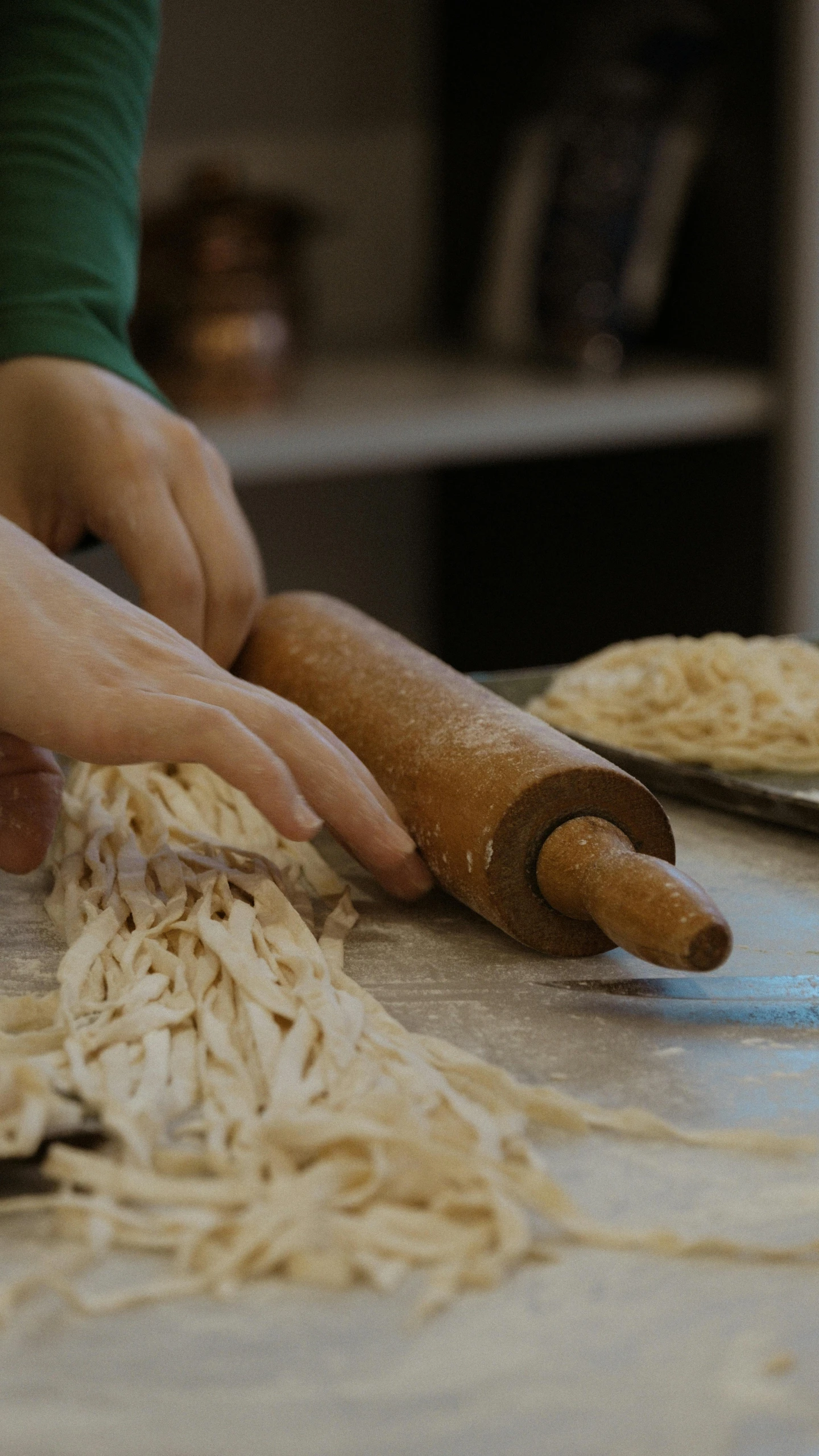 a pair of hands are rolling pasta on a counter