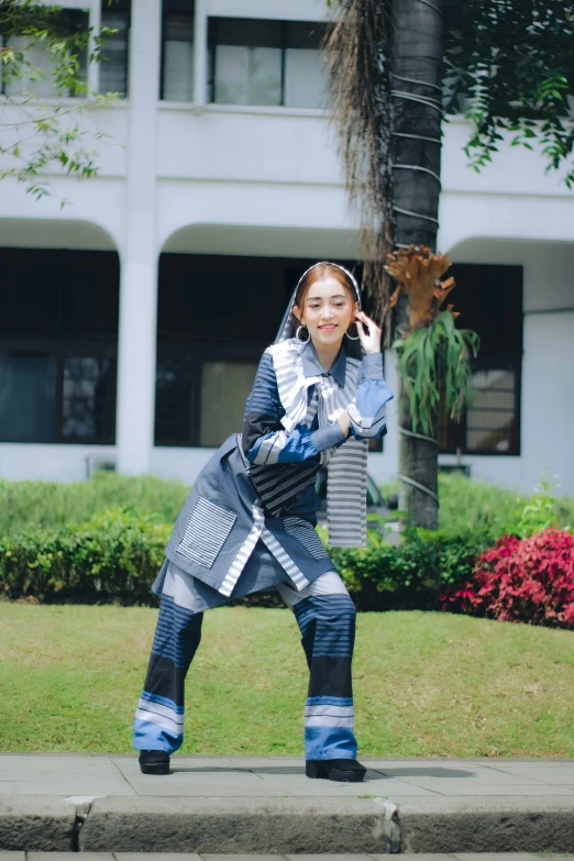 girl in blue patterned outfit standing on concrete curb