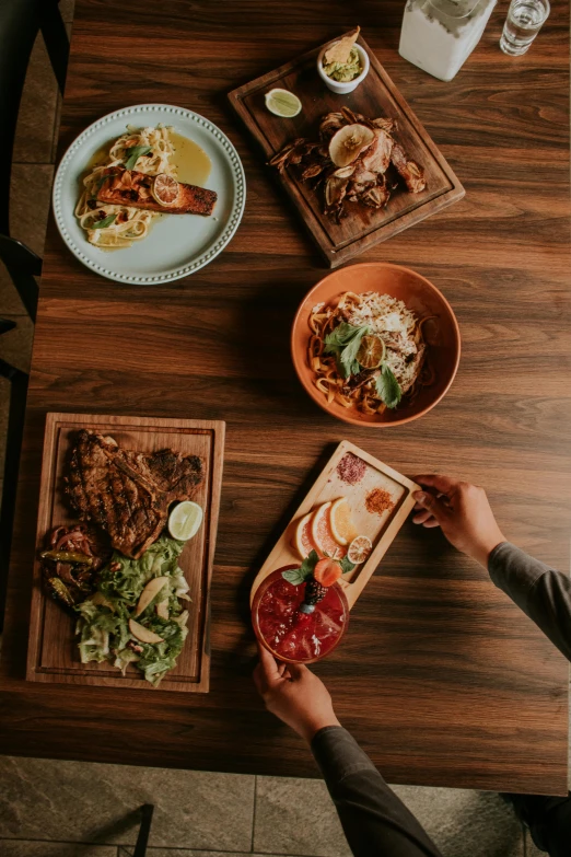 a person reaches into a bowl, plated food, and another plate of food