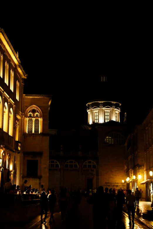 people walking down the sidewalk at night near a lit building