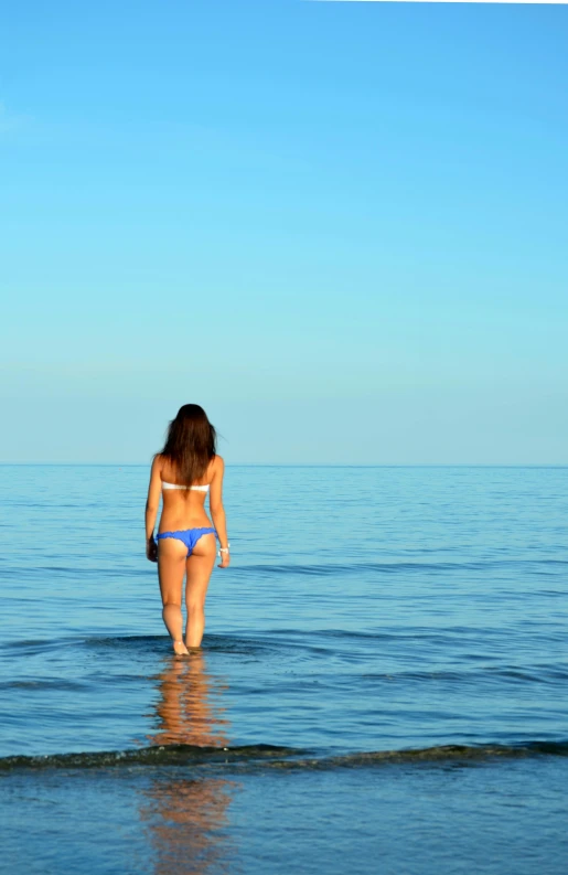 the back of a women who is walking in the water