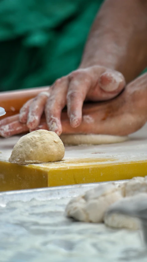 the hands of a person making dough in a kitchen