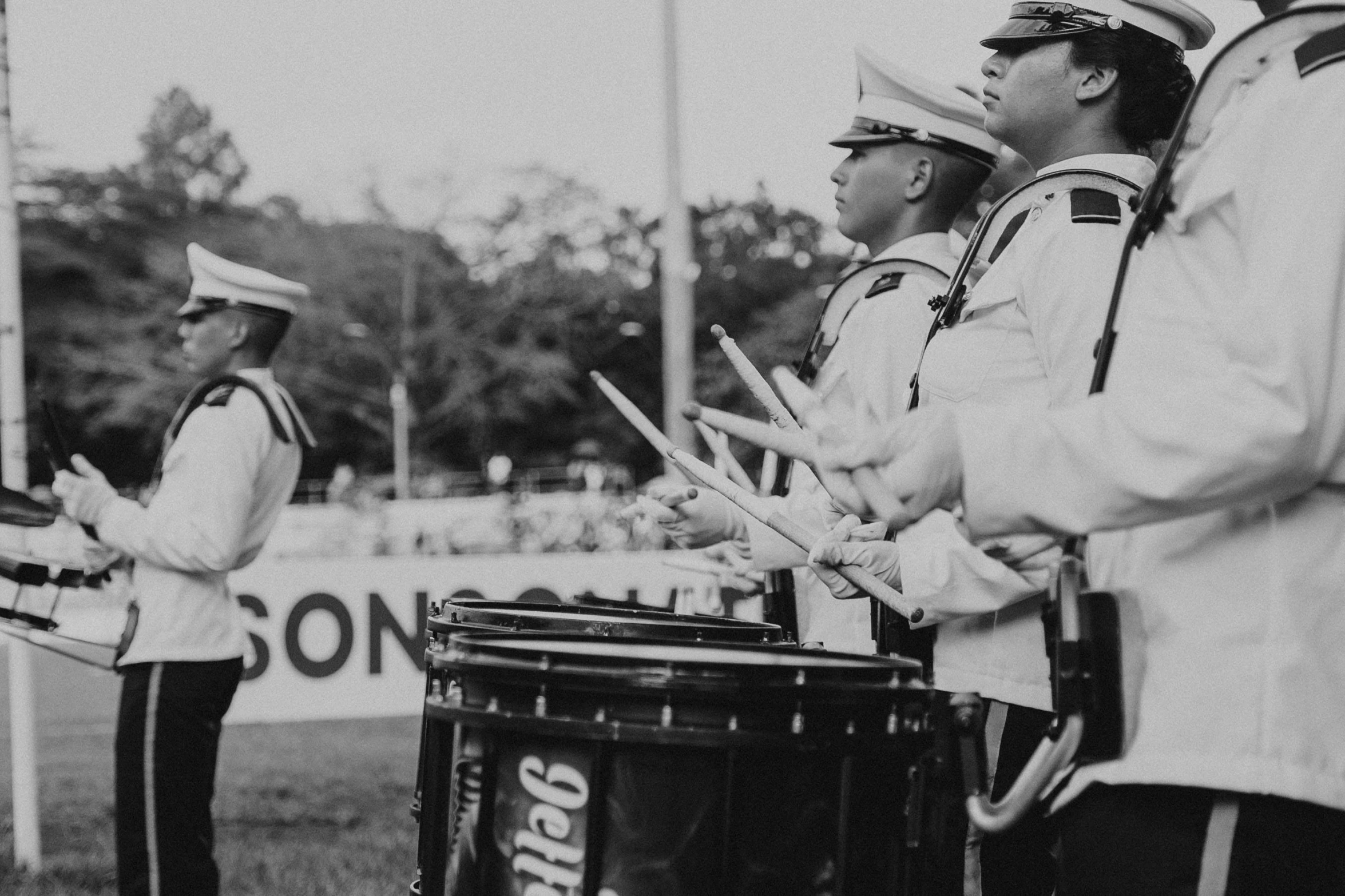 people in uniform, drumming on steel drums