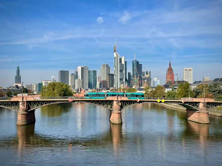 a commuter train crosses a bridge with city skylines in the background