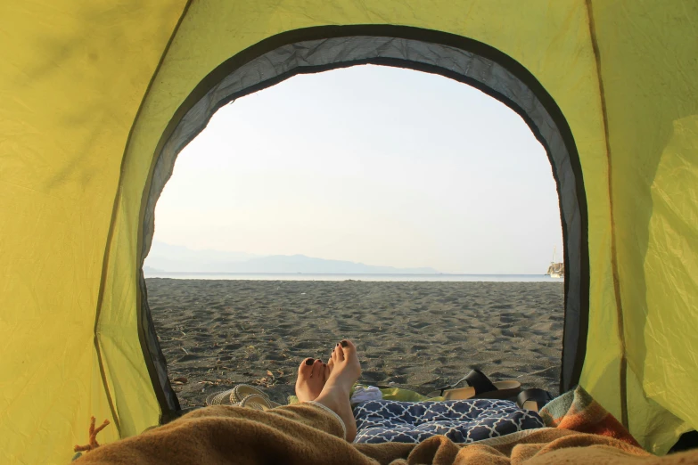 two people in their camping chairs have feet up inside the tent