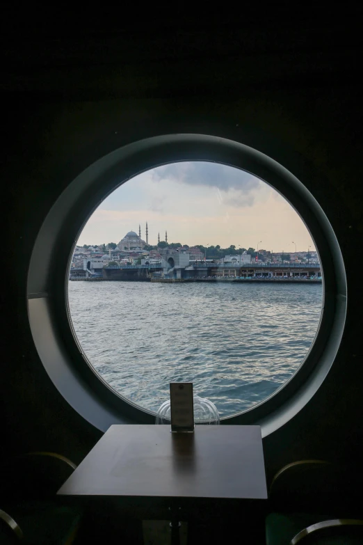 the view through a round window with a lighthouse in the distance