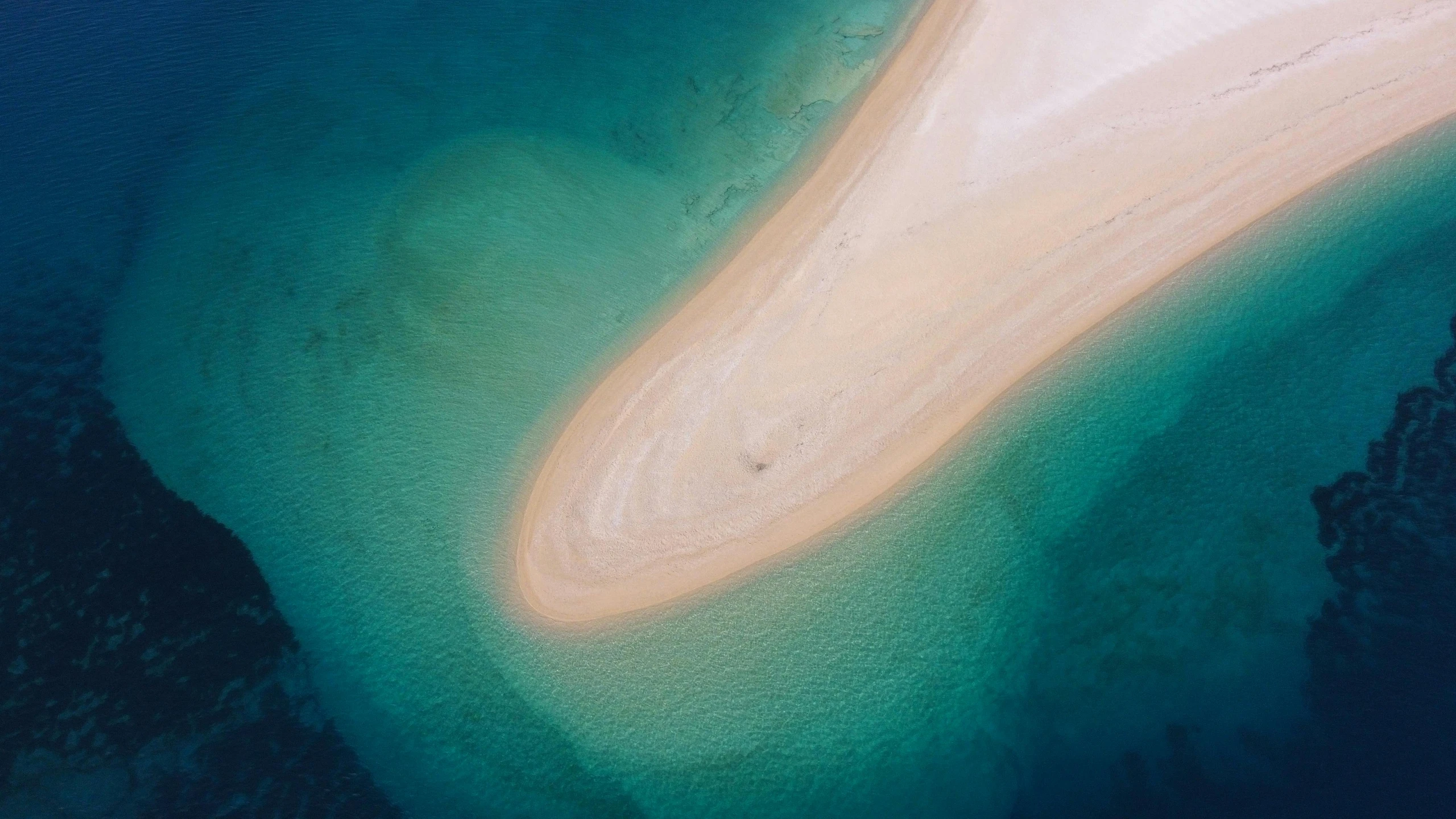 an aerial view of blue water and sand with a white beach