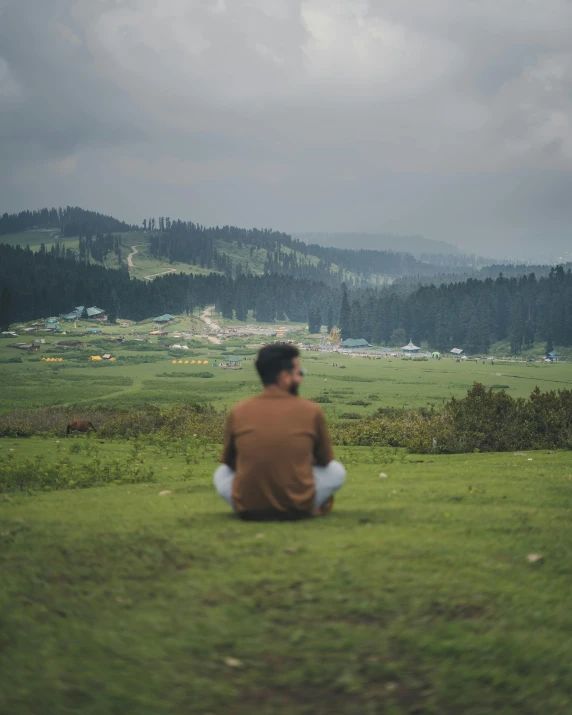 a man sitting in the grass on a hill