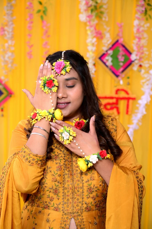 the woman is wearing yellow clothing and putting flowers in her hair