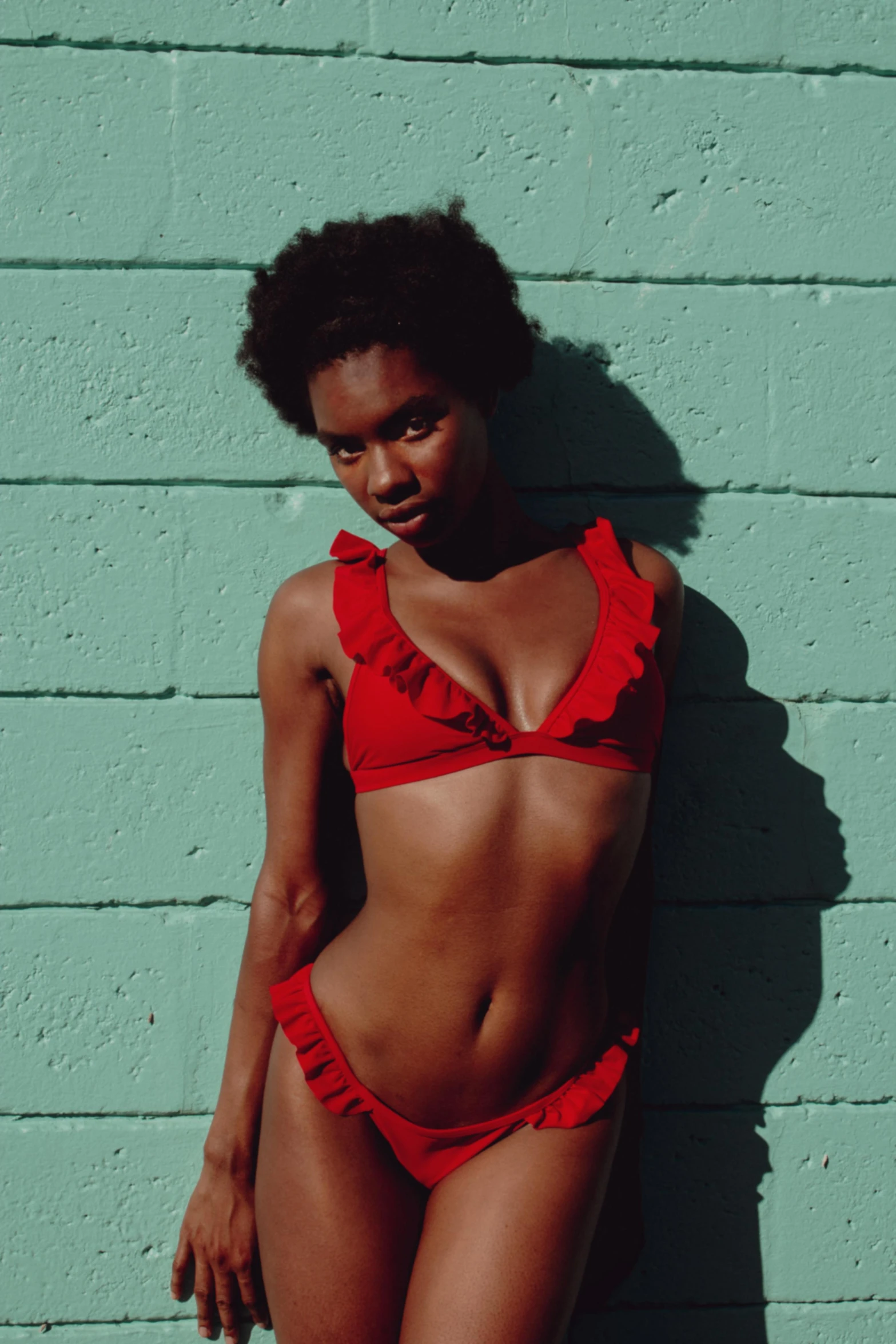 woman in a red swimsuit standing against a blue wall