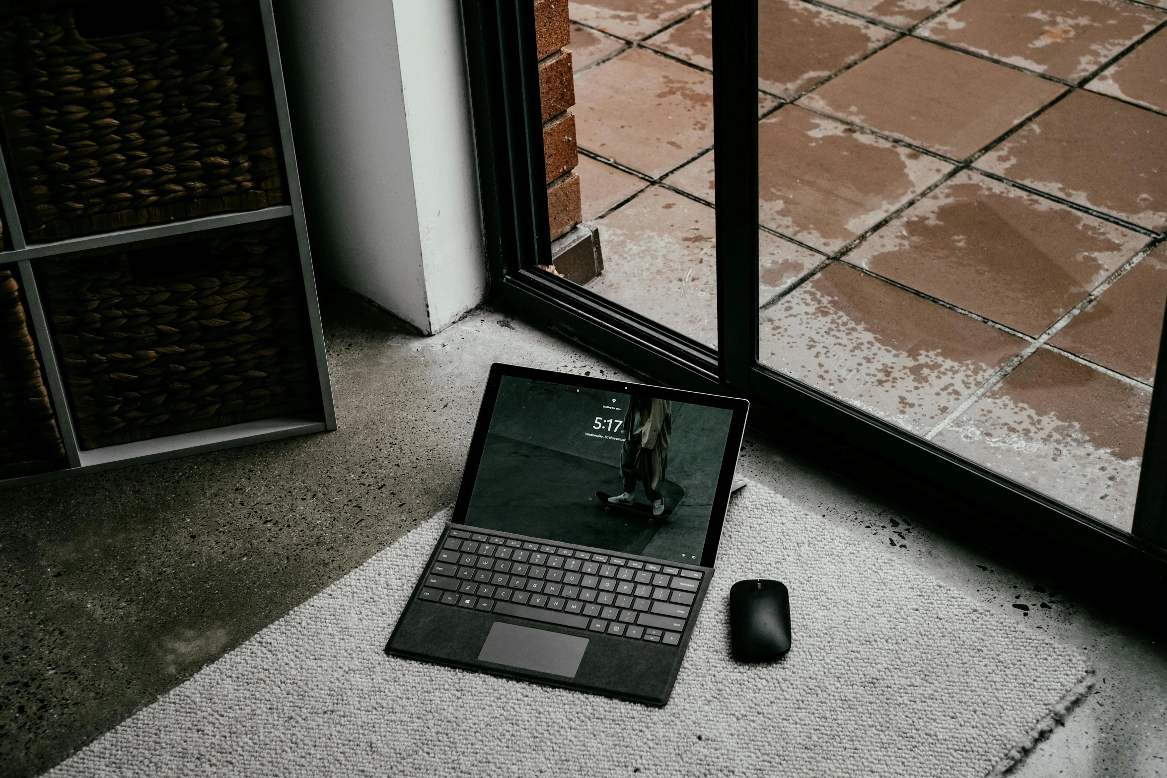 a laptop and mouse on the ground in front of a window