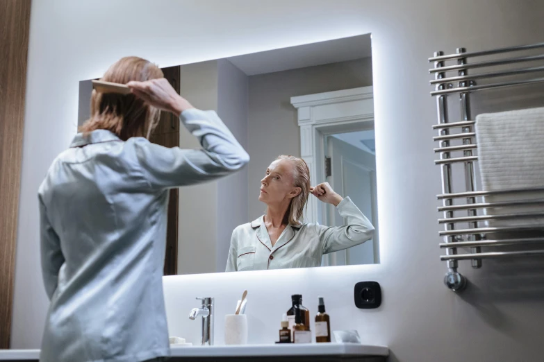 a woman is brushing her hair in a mirror
