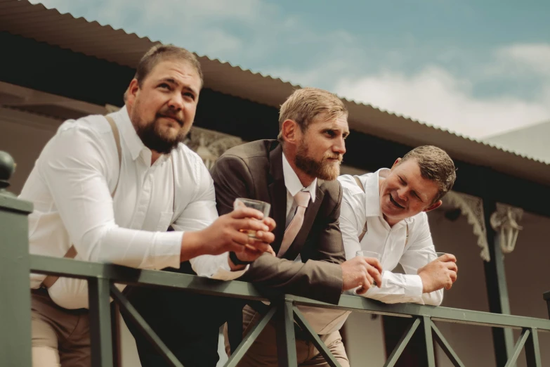 three men leaning on a rail in front of a building