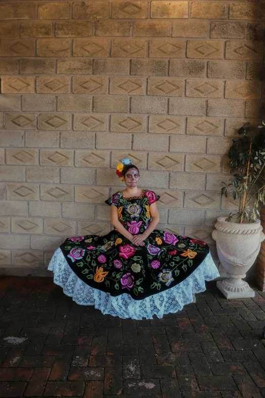 a girl dressed in an ornate mexican dress with flowers on her hair