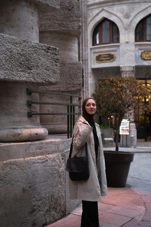 a woman with a handbag poses for the camera in front of an ornate building