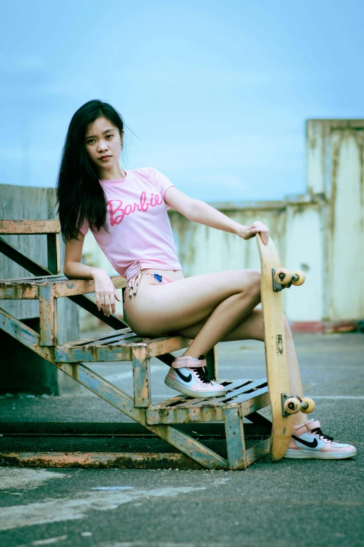 young woman holding skate board next to bench