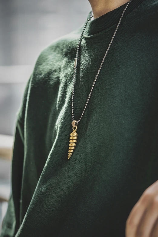 a young man is wearing a green sweater and a necklace