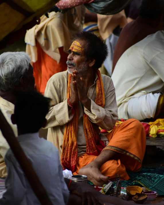 a man in a white and orange outfit talking to a group of people