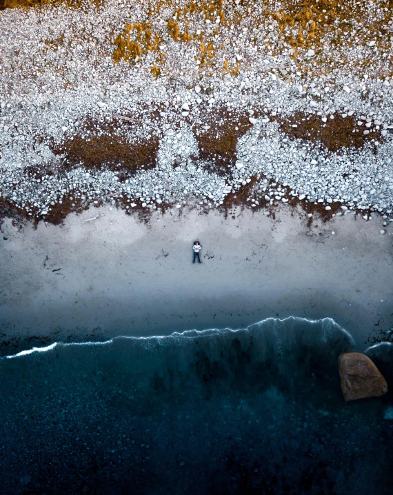 a man is standing alone on a sandy beach