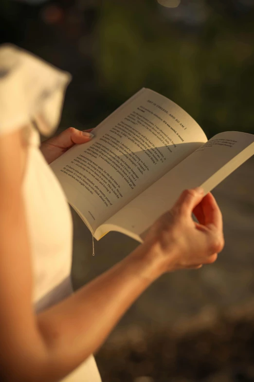 woman in a white dress holding a book