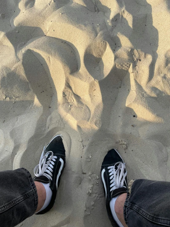 a person stands in the sand with their shoes on