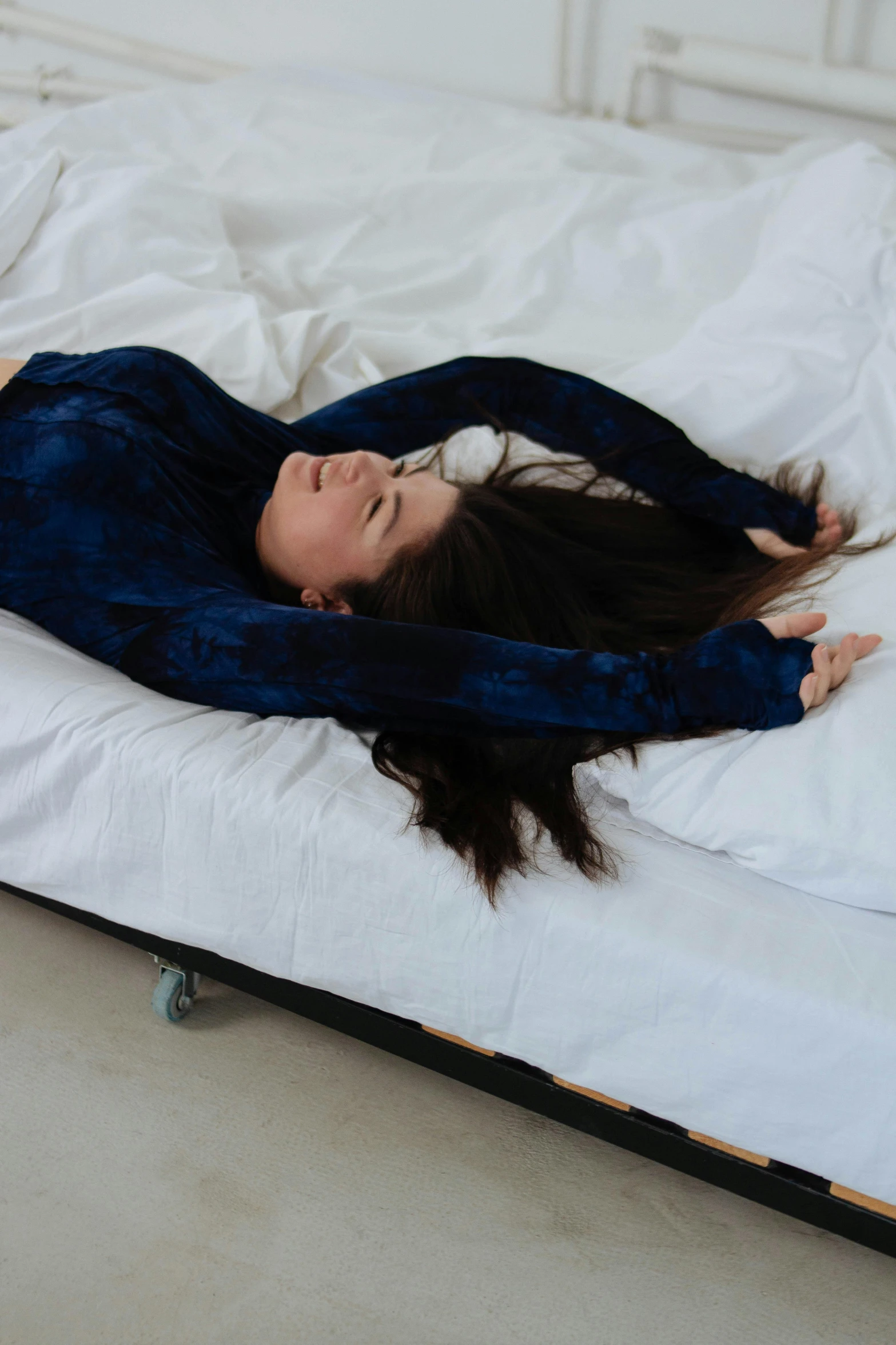 a young woman with dark hair is laying on her bed