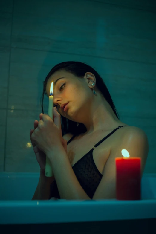 a woman in a bath with a candle in her hand