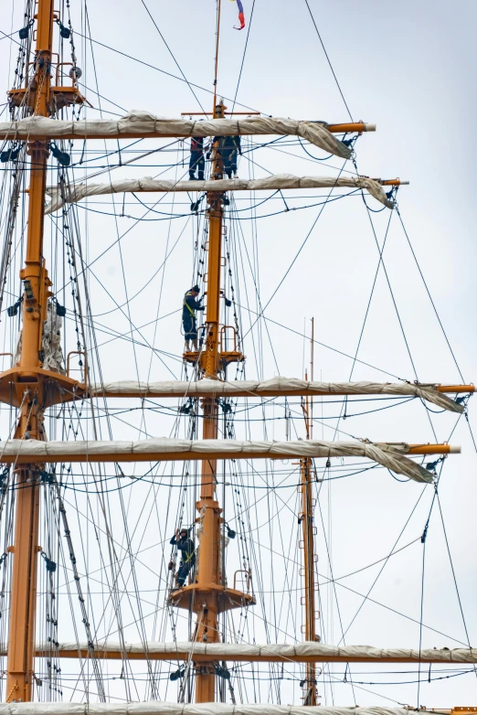 a group of people on the ropes of a tall mast ship