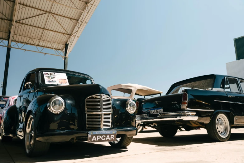 two old fashioned cars parked under a tent