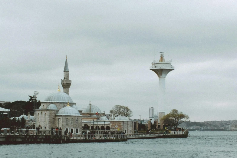 two towers sitting in the background while people walk on the boardwalk