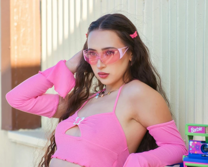 a young woman is wearing pink and has large sunglasses