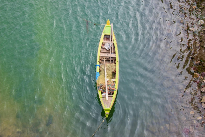 a green boat floating on top of the ocean