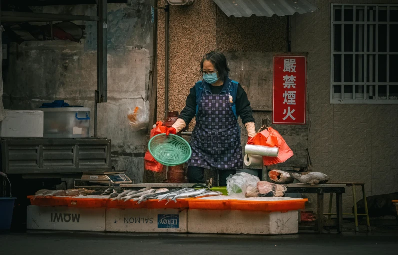 a person with an apron on buying fish at a stand