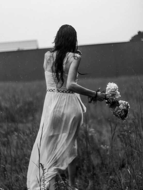 a woman standing in a field holding flowers