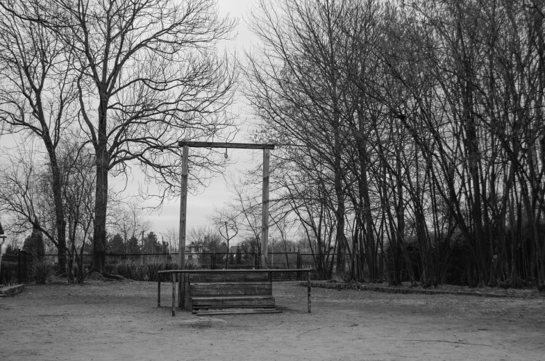 an empty park bench is next to some trees