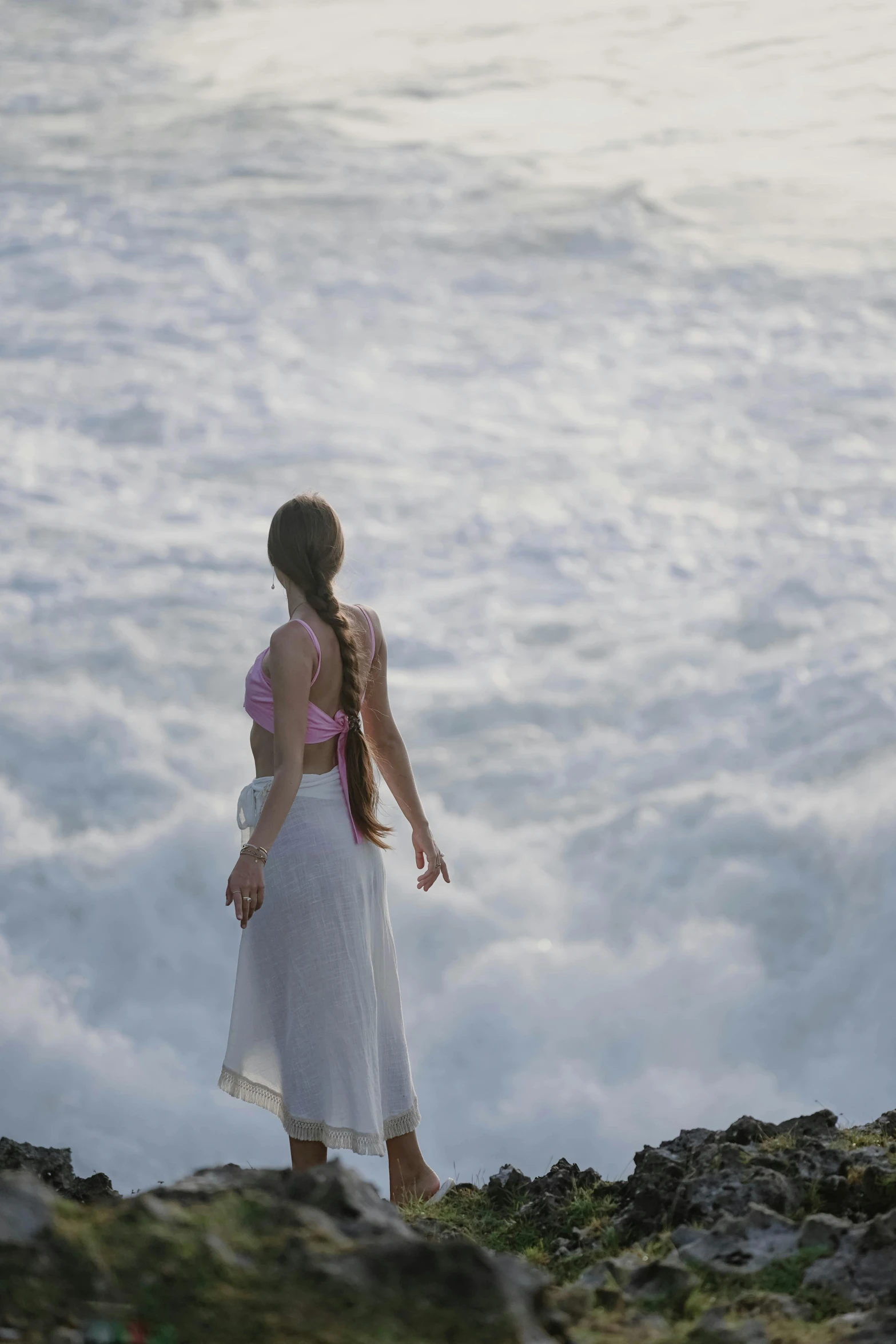 woman standing on rocks looking over the ocean