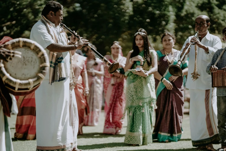 the man plays an instrument while others look on