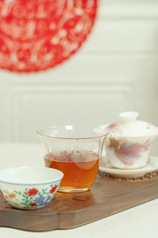 a tray topped with cups and saucers next to a tea pot