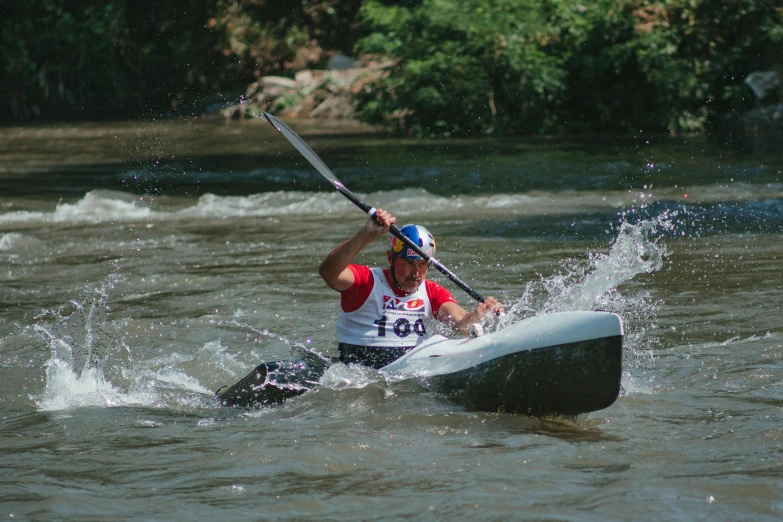 a man paddles a kayak through some shallow water