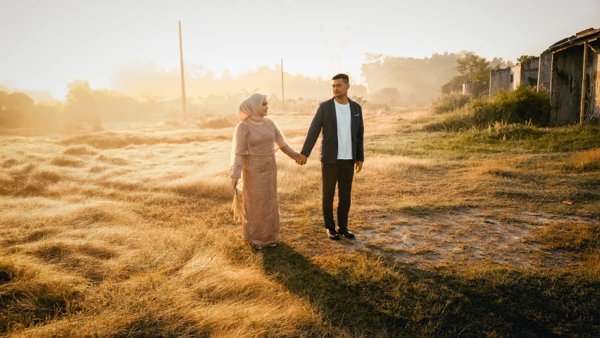 a couple in the foreground standing together on an empty field