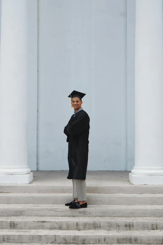 a man in a graduation gown posing for the camera